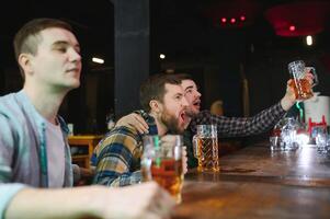 Soccer fans at the bar. Happy football fans cheering at bar and drinking beer while bartender serving beer at the background photo
