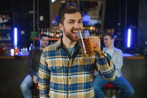 Tasting a good beer. Portrait of thoughtful men drinking beer at the bar photo
