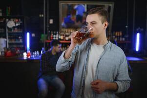 Night in bar. Portrait of cheerful men drinking beer at the bar photo