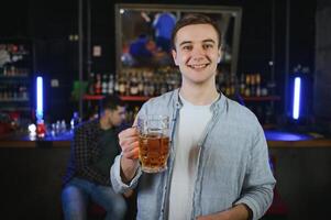 Handsome bearded man drinking beer at the bar counter in pub photo