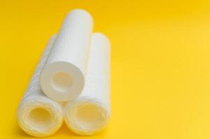 Water filters. Carbon cartridges and a glass on a yellow background. Household filtration system photo