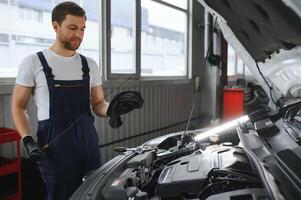 Auto mechanic checking the oil level in car engine,inspects engine water level dipstick,concept of checking the engine oil level every time before leaving. photo