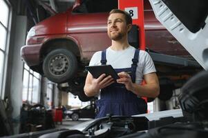 Automobile computer diagnosis. Car mechanic repairer looks for engine failure on diagnostics equipment in vehicle service workshop photo