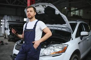Automobile computer diagnosis. Car mechanic repairer looks for engine failure on diagnostics equipment in vehicle service workshop photo