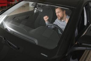 Successful and happy. Shot of a happy mature man smiling to the camera sitting in his brand new car at the local dealership photo