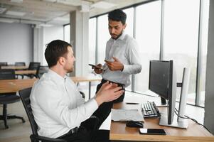 Two men traders sitting at desk at office together monitoring stocks data candle charts on screen analyzing price flow smiling cheerful having profit teamwork concept photo