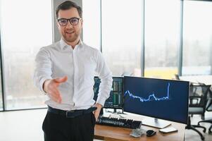 Young bearded man trader at office at table looking camera smiling cheerful photo