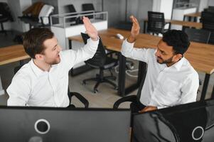 Two successful trader sitting in office and looking at screen, checking cryptocurrency information data on finance market graph, pointing on monitor photo
