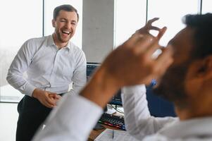 Two successful trader sitting in office and looking at screen, checking cryptocurrency information data on finance market graph, pointing on monitor photo