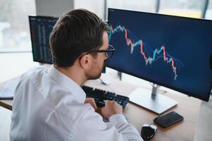 Serious business man trader analyst looking at computer monitor, investor broker analyzing indexes, financial chart trading online investment data on cryptocurrency stock market graph on pc screen. photo