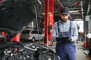 Professional caucasian car mechanic with checklist standing by vehicle engine area with hood open detecting malfunction photo