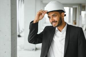 Asian engineer handsome man or architect with white safety helmet in construction site. Standing at modern building construction. Worker asian man working project building photo