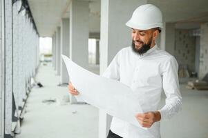 Young attractive arabic industrial engineer in hard hat. Professional and industry, builder architect job, worker checking work at plant indoor photo