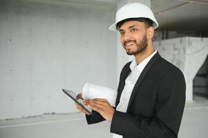 Confident asian engineer man Using tablet for checking and maintenance to inspection at modern home building construction. Architect working with white safety helmet in construction site. photo
