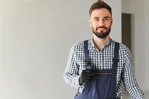 Portrait of handsome mechanic with stubble in blue overall, shirt having his arms crossed, looking at camera photo