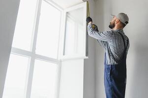 Worker in installing white plastic upvc window on house. photo