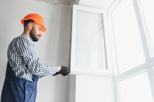 Worker installing plastic window indoors photo