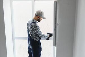 service man installing window with screwdriver photo