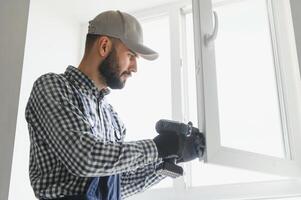 Worker installing plastic window indoors photo