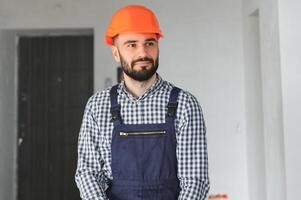 Portrait of positive, handsome young male builder in hard hat photo