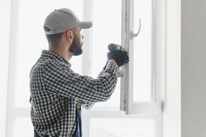 service man installing window with screwdriver photo
