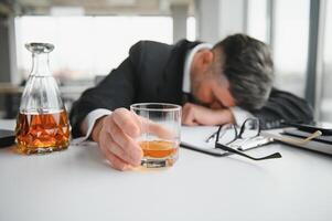 Alcoholism at work. Tired employee drinking alcohol at workplace, can not handle stress photo