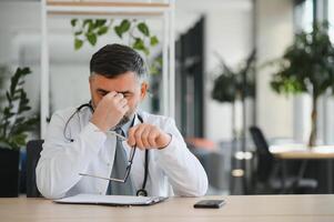 Senior caucasian man wearing doctor uniform and stethoscope at the clinic rubbing eyes for fatigue and headache, sleepy and tired expression. vision problem photo