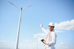Indian Engineer working at alternative renewable wind energy farm - Sustainable energy industry concept photo