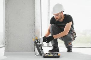 electrician installs socket boxes on the wall and puts a putty on them photo