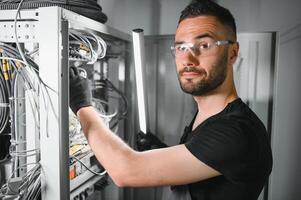 Repairman is busy and working with internet equipment and wires in server room photo