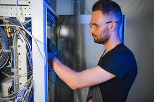 Repairman is busy and working with internet equipment and wires in server room photo
