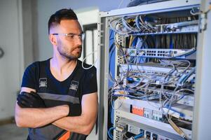 A technician works with server equipment in a data center. A man commutes wires in a server room photo