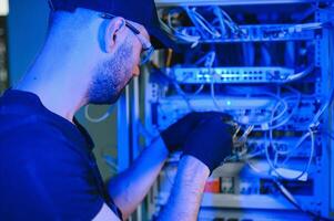 Repairman is busy and working with internet equipment and wires in server room photo