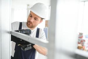 Construction worker installing metal profile for interior partition wall, while building a new house or renovation process, viewed from his back. photo