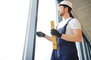 Worker using bubble level after plastic window installation indoors photo