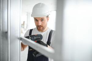 Construction worker installing metal profile for interior partition wall, while building a new house or renovation process, viewed from his back. photo