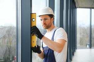 Worker using bubble level after plastic window installation indoors photo
