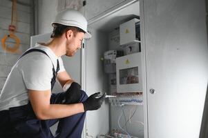A male electrician works in a switchboard with an electrical connecting cable. photo