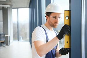 Worker using bubble level after plastic window installation indoors photo