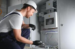 Man, an electrical technician working in a switchboard with fuses. Installation and connection of electrical equipment. Professional with tools in hand. concept of complex work, space for text. photo