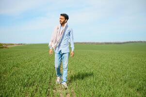 Portrait of farmer standing in a wheat field. farmer stands in green wheat field, looks, examines his crop photo