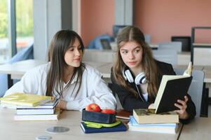 Education. Two clever modern students in black and white uniform study in a library sitting at a table with books. Modern generation. Students. photo