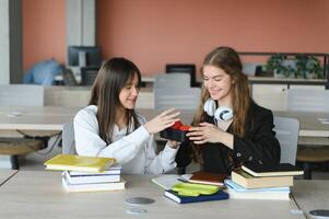 A cute girl smiling at her classmate while having lunch at the desk in school during a break photo