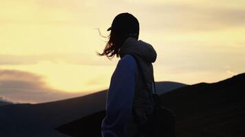 Back view of woman with cap and packpack admiring twilight. video