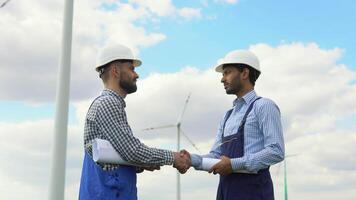 Indian and caucasian workers handshake after inspection work in wind turbine power generator station video