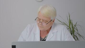 Therapist typing on laptop makes research taking notes on paper checklists. video