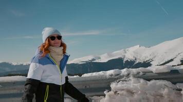 Shot of snowy mountains peaks and a woman smiling on camera while walking. video