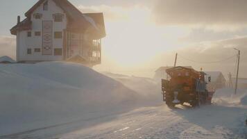 Snow plow cleans the mountain road from snow while wind is blowing. video