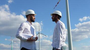 Indian and caucasian engineers handshake after inspection work in wind turbine power generator station video