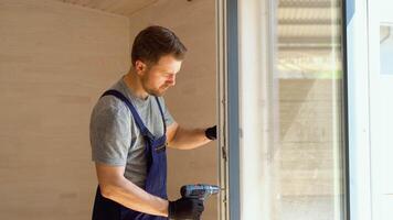 Service man in uniform installs pvc windows in new wooden hotel room video